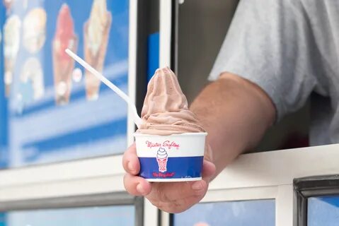 A man holds a cup of chocolate soft serve in a Mister Softee cup with a spo...