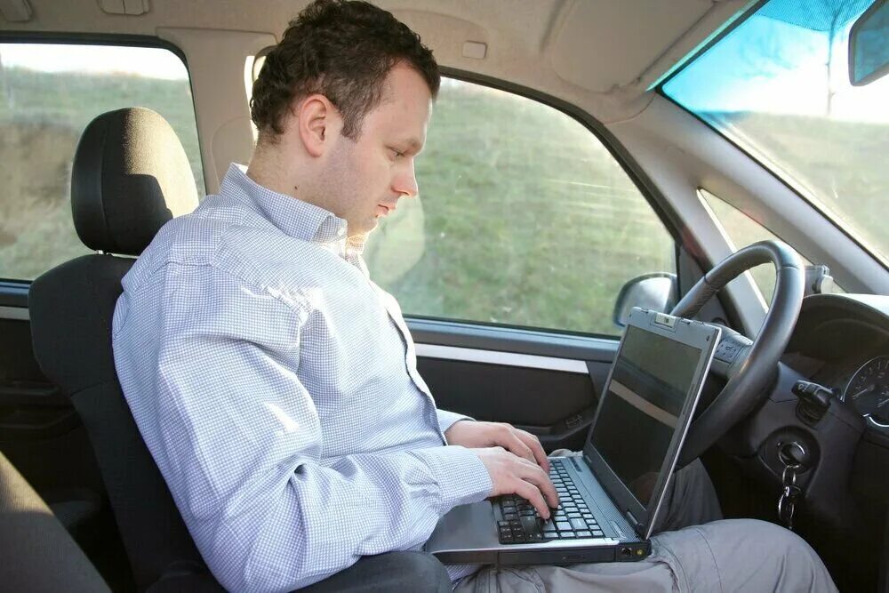 During driving. Бизнесмен в автомобиле. Водитель с ноутбуком. Бизнесмен с ноутбуком в машине. За компьютером в машине.