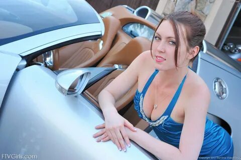 Redheaded babe shows her boobs and ass next to a really fancy car.