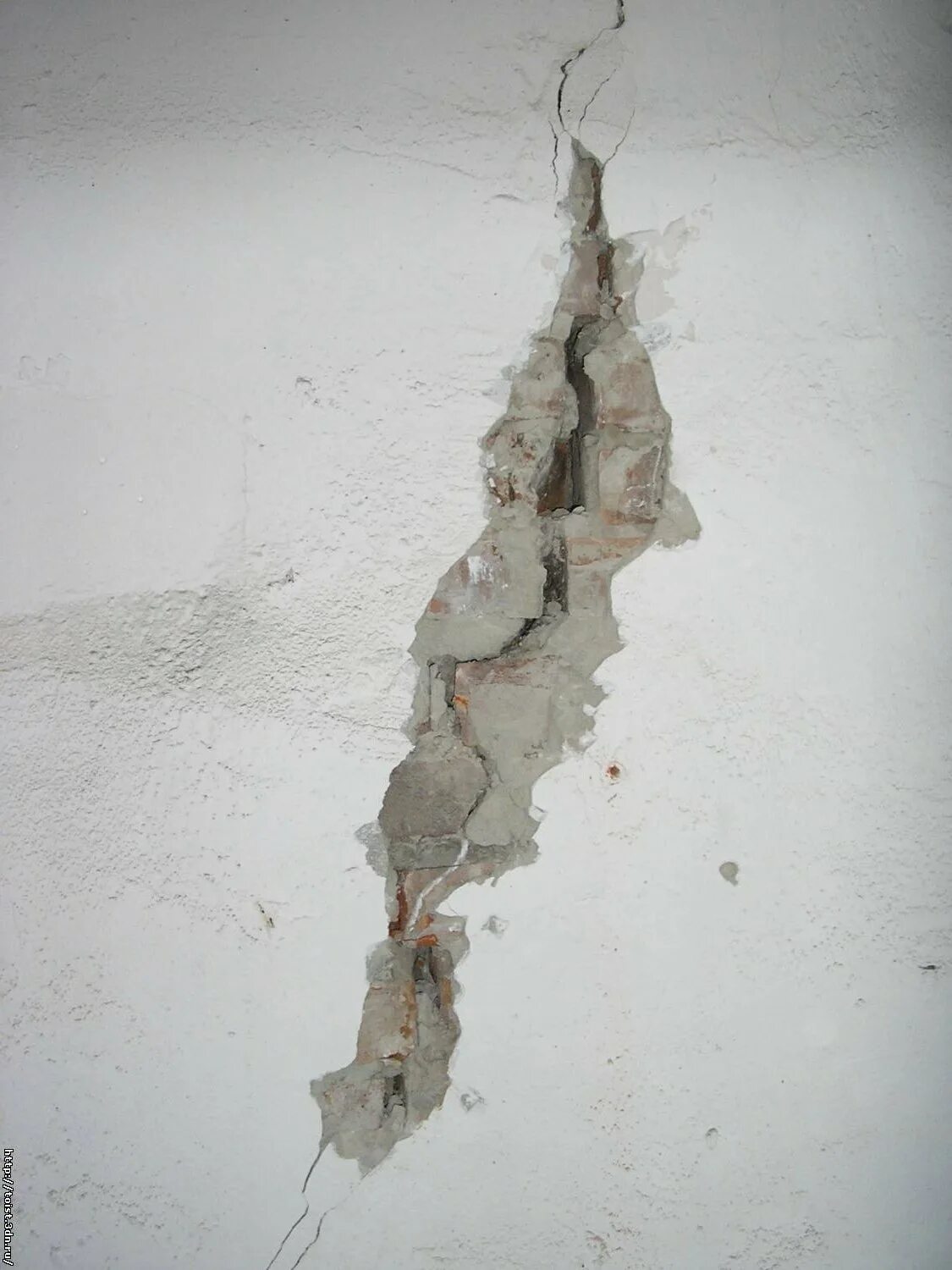 Отслоение штукатурки и отделочного слоя. Трещины на штукатурке. Трещины в панельном доме. Мелкие трещины на стене.