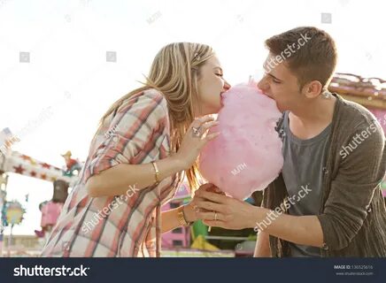 Young Fun Couple Biting Into A Cotton Candy Floss Sweet At The Same.