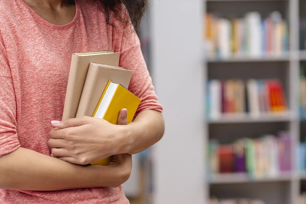 Читать книгу без рук. Стопка книг в руках. девушка со стопкой книг. девушка несёт стопку книг. девушка держит стопку книг.