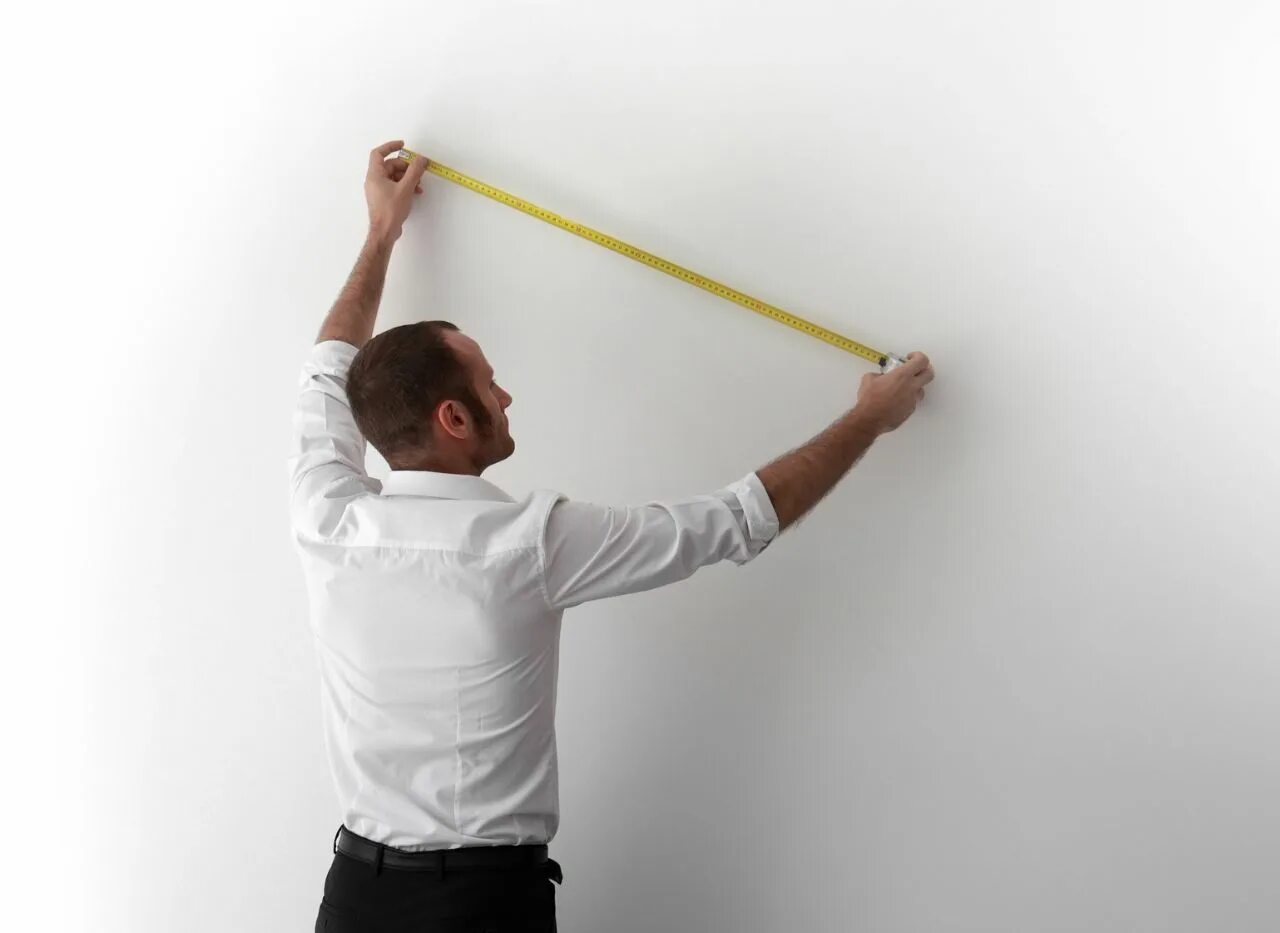 Работа рулеткой. Измерение стен. померить стену. мужчина измеряет стену. мужчина измеряет рулеткой.