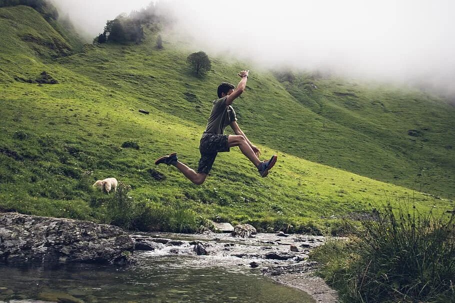 Время на природе со своей. Человек перепрыгивает. Человек в прыжке. Перепрыгивает в горах. Прыжок через горы.