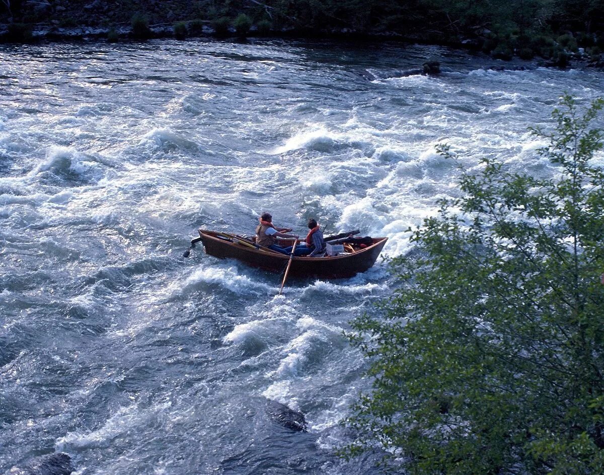 Рассекая воду плывет по реке. Река Маккензи. Лодка дори Маккензи. Лодка на реке. Лодка для горных рек.