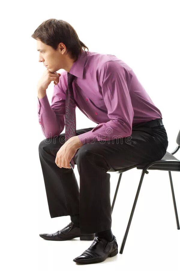 Мужчина сидит на белом фоне. Человек сидит на стуле вид сбоку. Мужчина сидит впрофилт. Ноги на столе. Человек сидит.