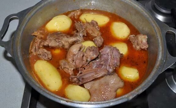 утка тушеная с овощами в казане. утиное мясо. тушеная утка в казане. шулюм из утки в казане на костре. тушеная утка в казане.