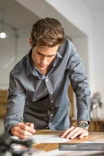 Стоит облокотившись на стол
