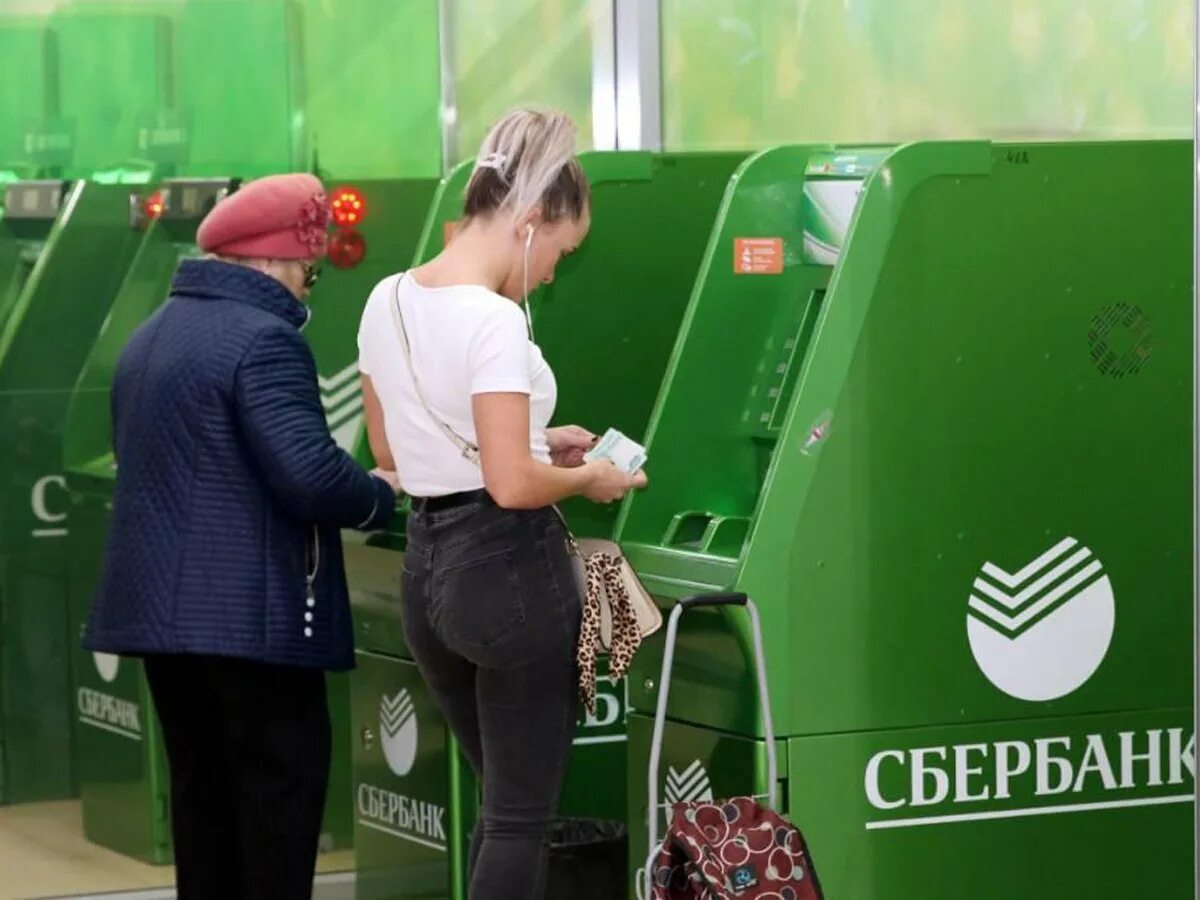 Сбербанк стоит снимать деньги. Деньги в банкомате. женщина у банкомата с деньгами. банкомат сбербанка. деньги возле банкомата.