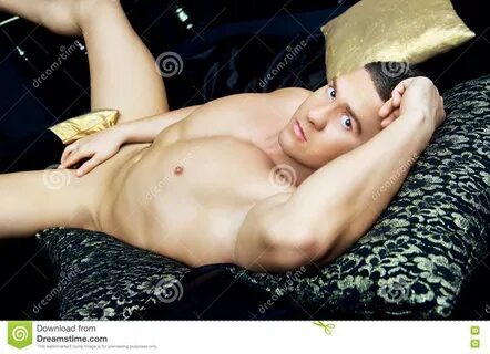 Hombre desnudo atractivo en cama con lino negro.