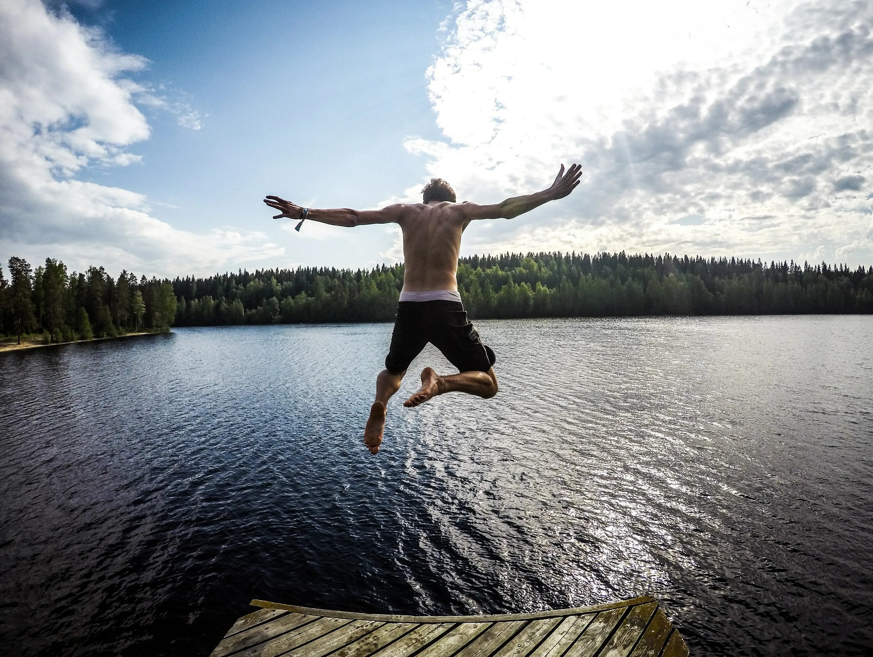 Человек прыгает в воду. Люди на озере. Прыжки в воду на озере. Мужчина прыгает в воду.