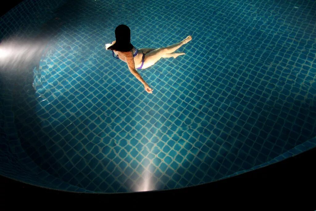 Девушка в бассейне ночью. Фотосессия в бассейне. Брюнетка в бассейне со спины. Ночной бассейн. Девушка в бассейне ночью.