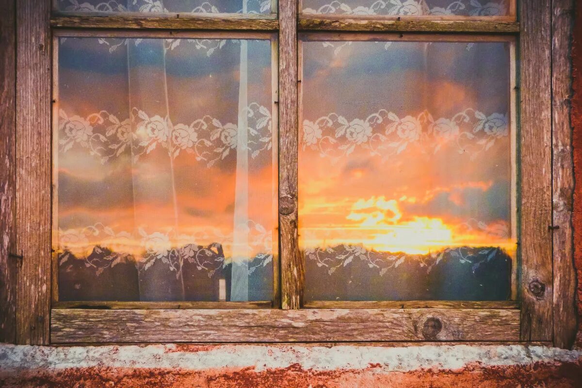 В окнах отражается солнце. Пейзаж за окном. Старинные окна. Вид из окна в деревне. Отражение в окне.