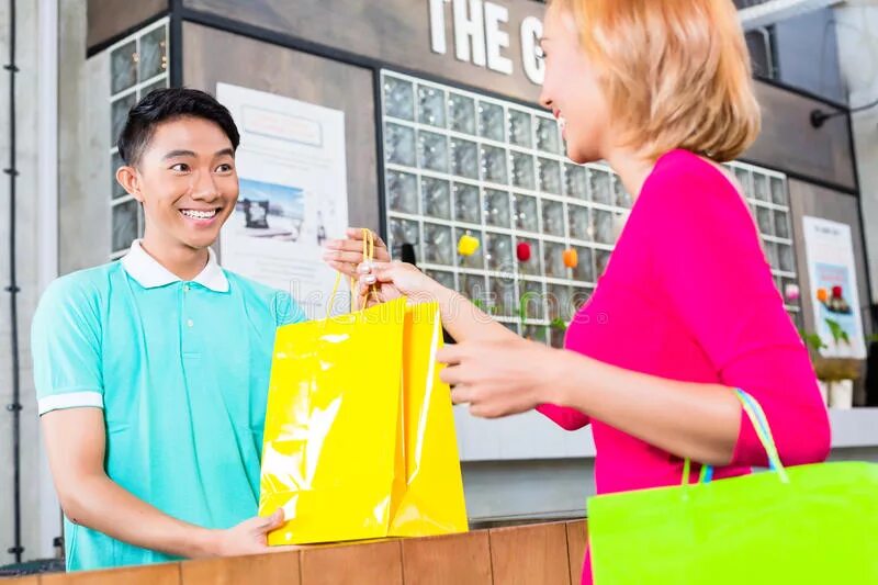 Refund shopping. Shop Assistant helping customers. Банки подталкивают к покупкам. Продавец передает покупку. Выбирая покупку или расплачиваясь сумку