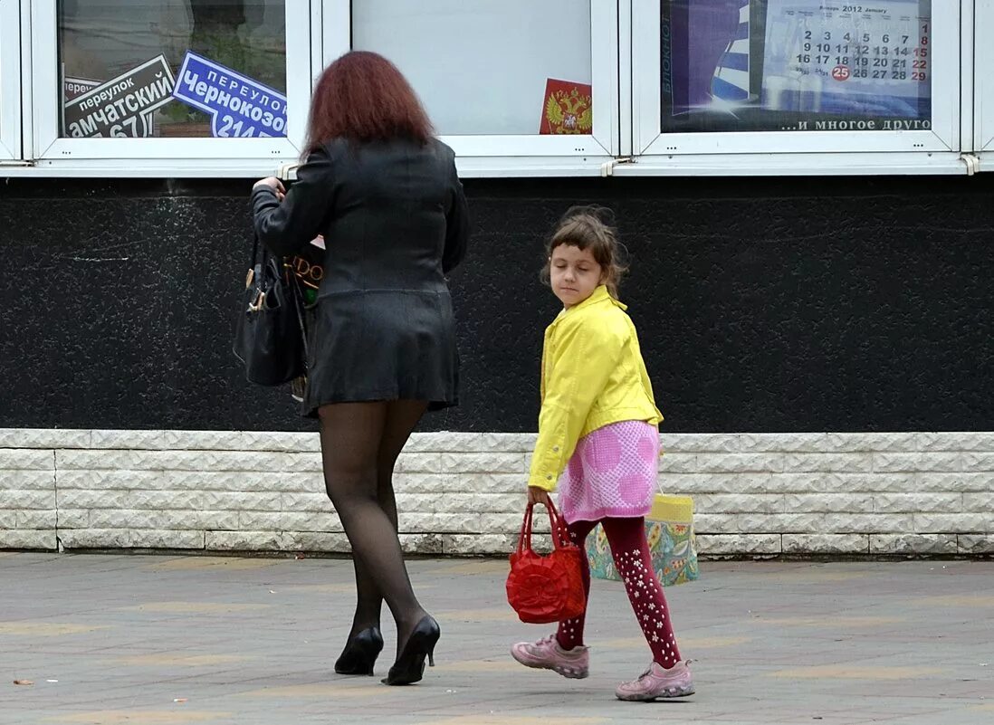 Мамаши в вызывающей одежде. Мать наклоняется к ребенку. Молодая мамочка наклонилась. Доченька нагнулась.