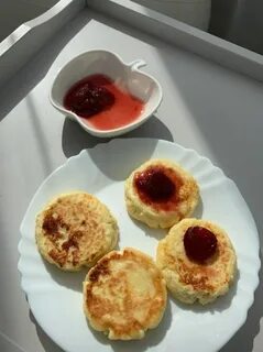 four pancakes on a white plate with jam in a small bowl next to the plates 