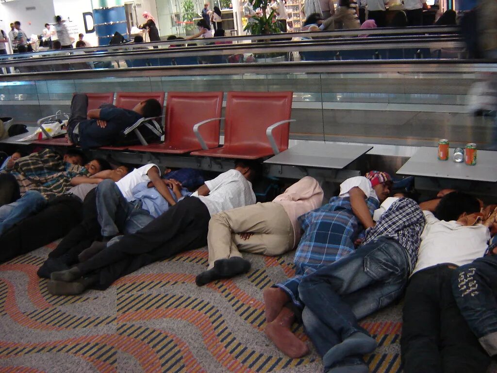 Развлечения на вокзалах. Люди спят в аэропорту. Человек спящий в аэропорту.