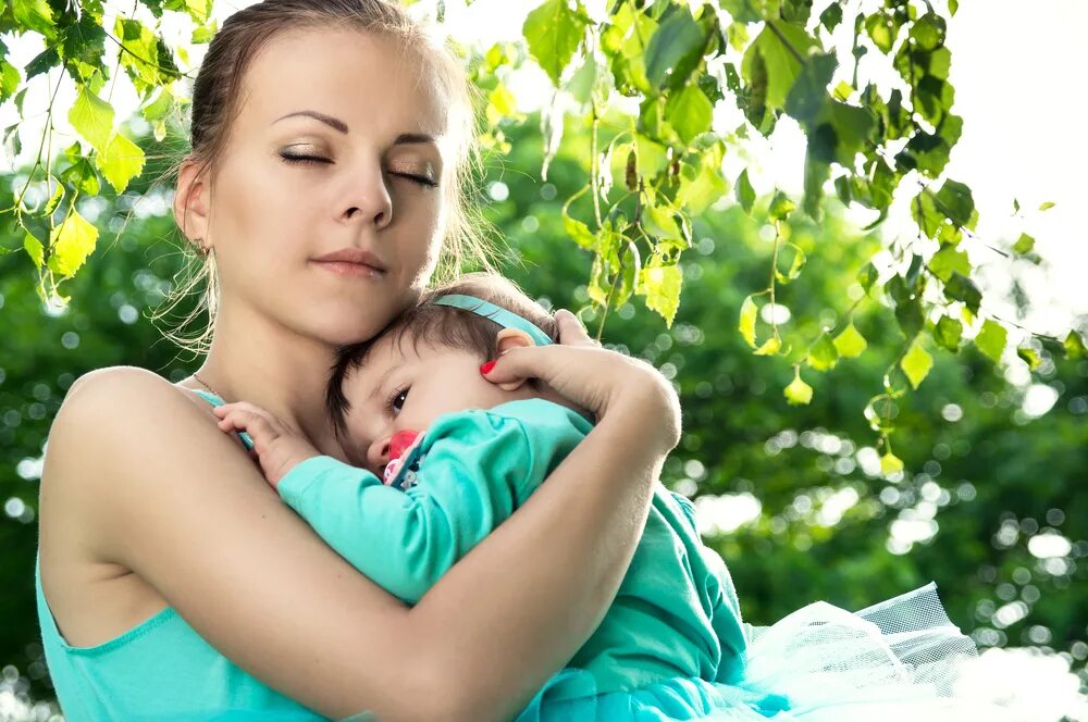 Young mother like. Мама обнимает ребенка на улице. Мама обнимает ребёнка на природе. Женщина в зеленом обнимает ребенка.