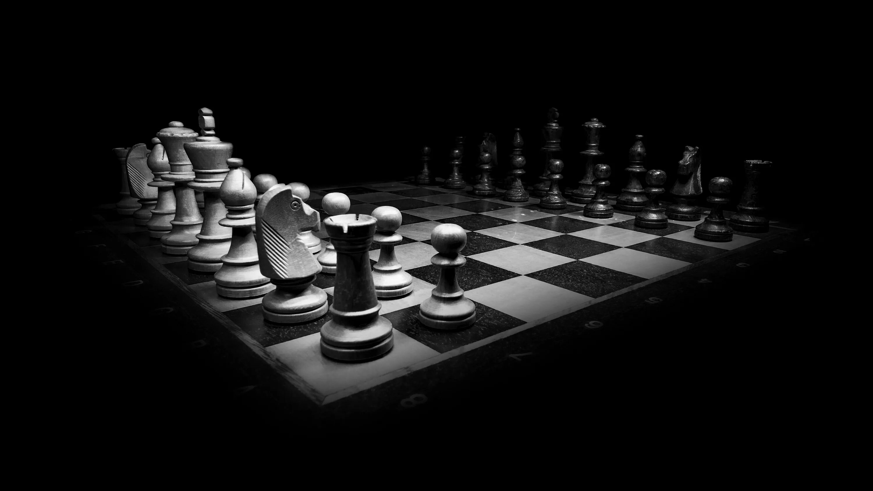 Игра черно белые камни на доске. Шахматная доска. Шахматные фигуры на черном фоне. Шахматный фон. Шахматная доска черно белая.