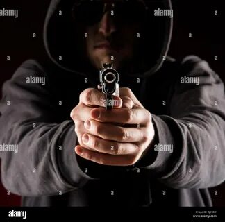 Killer with gun close-up on dark background Stock Photo. 