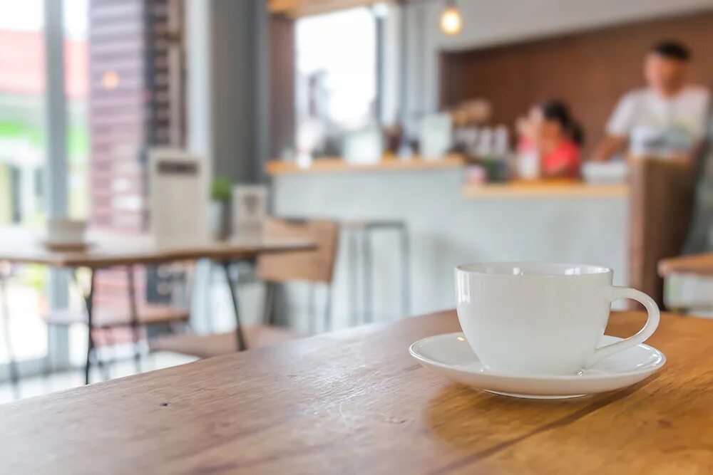 There two cups on the table. Белая чашка на блюдце и на столе с ноутбуком. фото фон стол с блюдцем. кружка на кухне на столе фото издалека. saucer on the table.