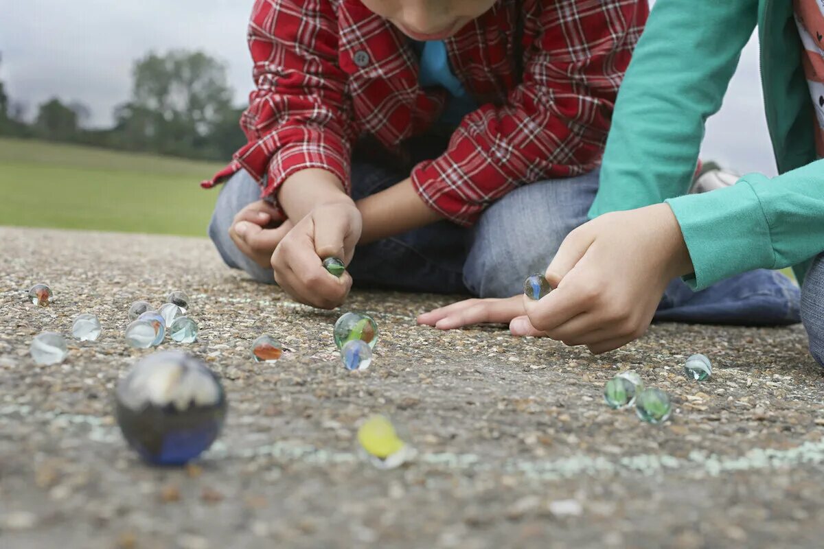 Игра шары стекло. Marbles игра. Дети играют с камешками. Игра в камешки. Камешки Марблс в руках детей.