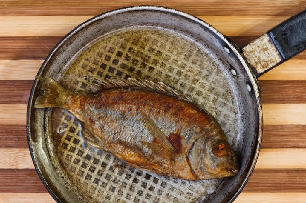 Жареная рыба в замасленной майке. Рыба на сковороде. Жареная рыба на сковородке. Рыбка на сковородке. Жареная рыба карась.