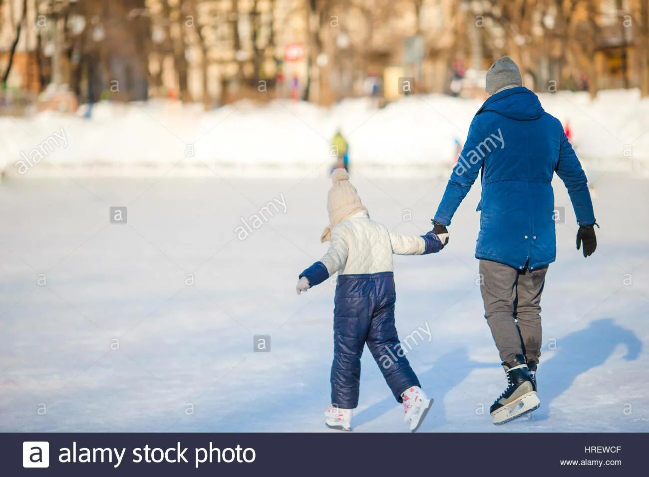 Папа учит кататься на коньках. Отец учит кататься на коньках. Папа с сыном на коньках. Мама учит малыша кататься на коньках.