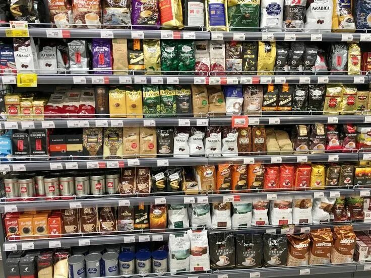 В магазине продается несколько видов кофе. Выкладка кофе в магазине. ассортимент кофе в магазине. выкладка чая и кофе в магазине. полки с кофе в магазине.