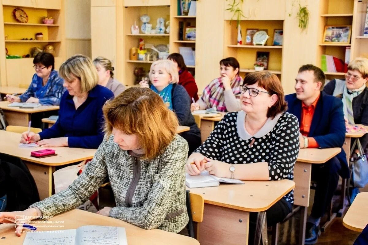 Учитель обсуждает родителей. Учитель за партой. Взрослые за партой. В школе взрослый за партой. Учителя на педсовете.