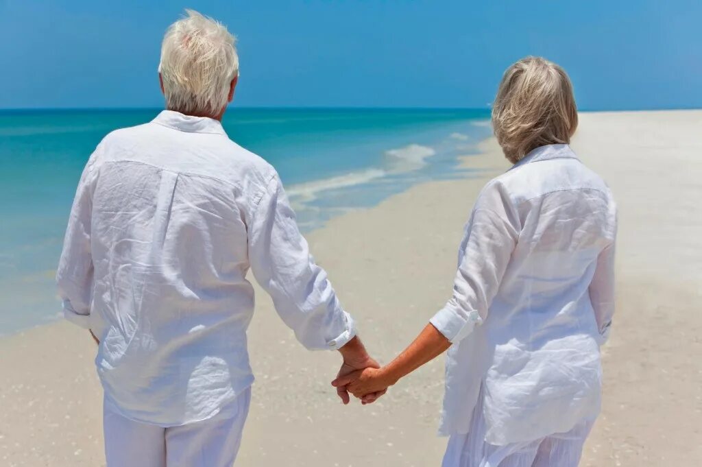 Пожилые держатся за руки. Супруги на берегу моря. Пожилая пара на море. Мужчина и женщина в белом. Влюбленная пожилая пара на море.