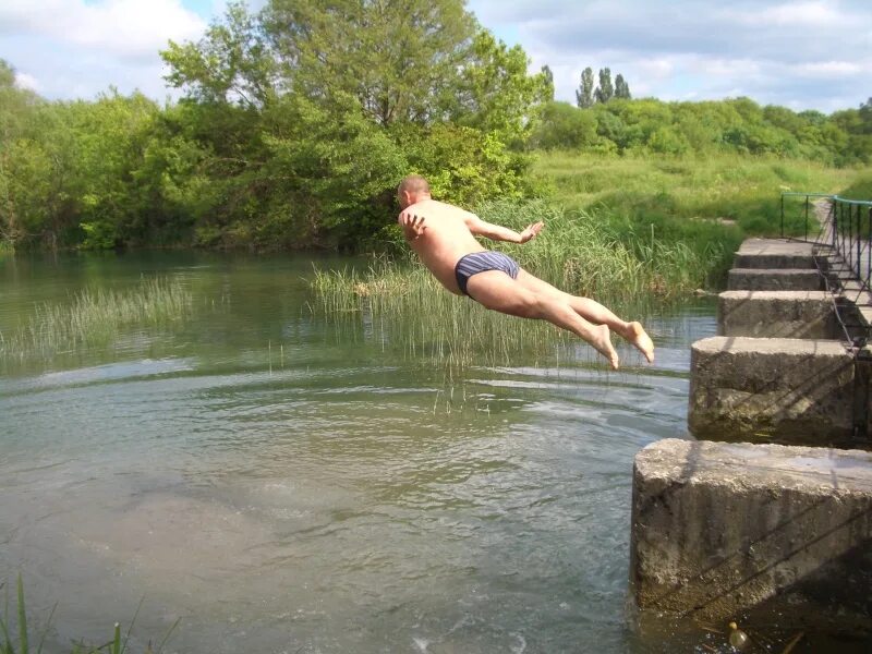 прыгает в речку. ныряние в воду. прыжок в речку. прыжки в воду.