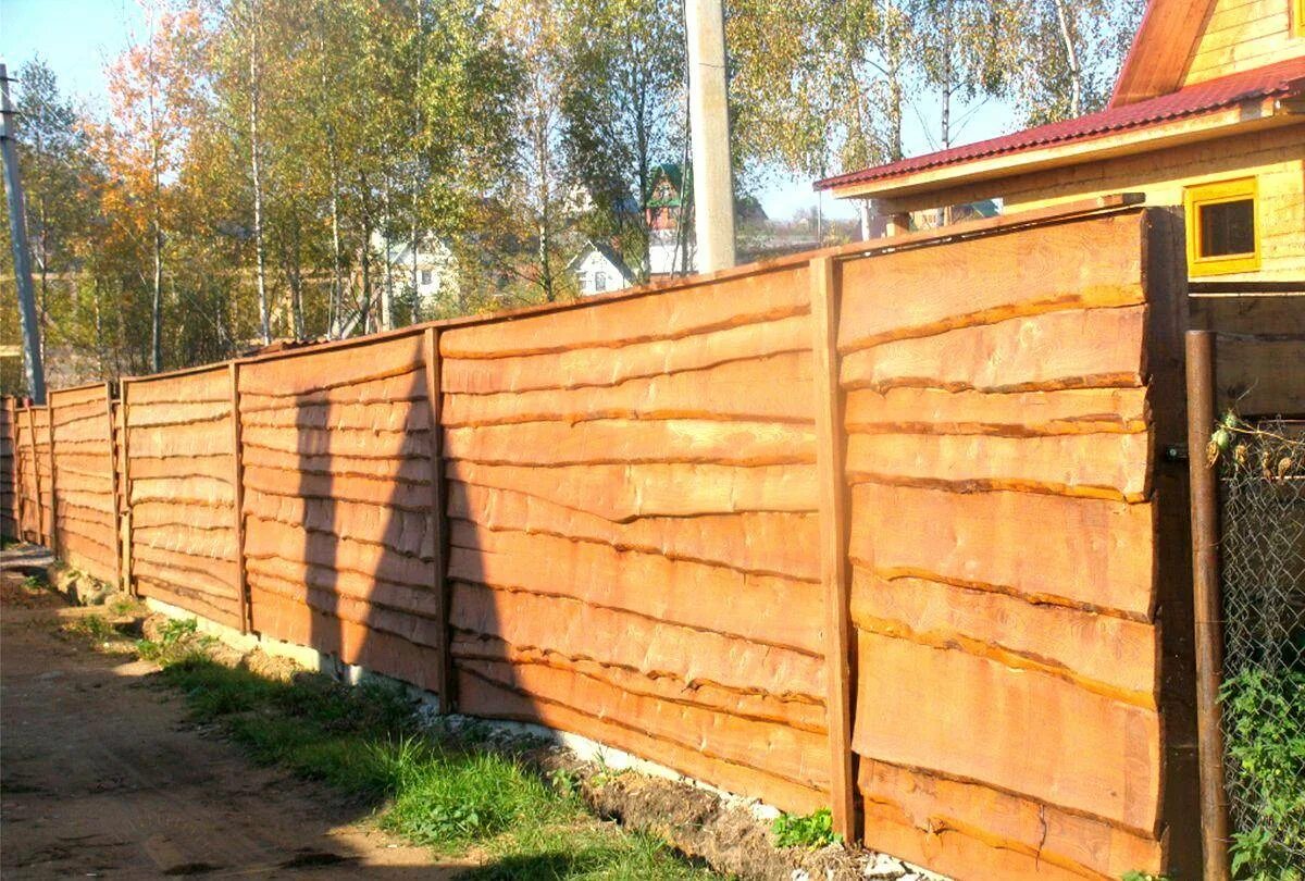 Из чего сделать бюджетный забор. Забор из горбыля 100мм. забор из горбыля горизонтальный. деревянный забор из необрезной доски. деревянный забор из горбыля.