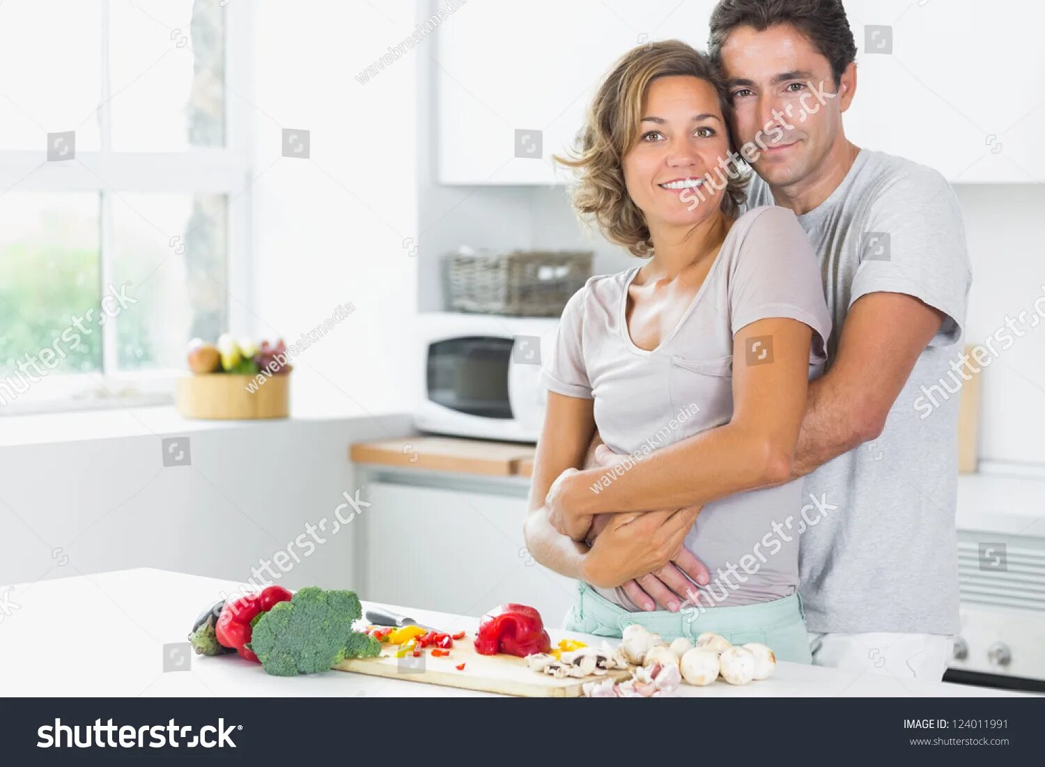Муж с женой на кухне занимаются. Пара на кухне. Муж обнимает жену с пирогами. Муж и жена улыбаются дома. Муж с женой Веселые на кухне фото.
