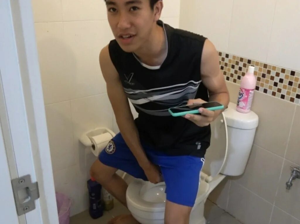 Asian boy sitting on toilet bowl - health problem concept фотография Stock Adobe