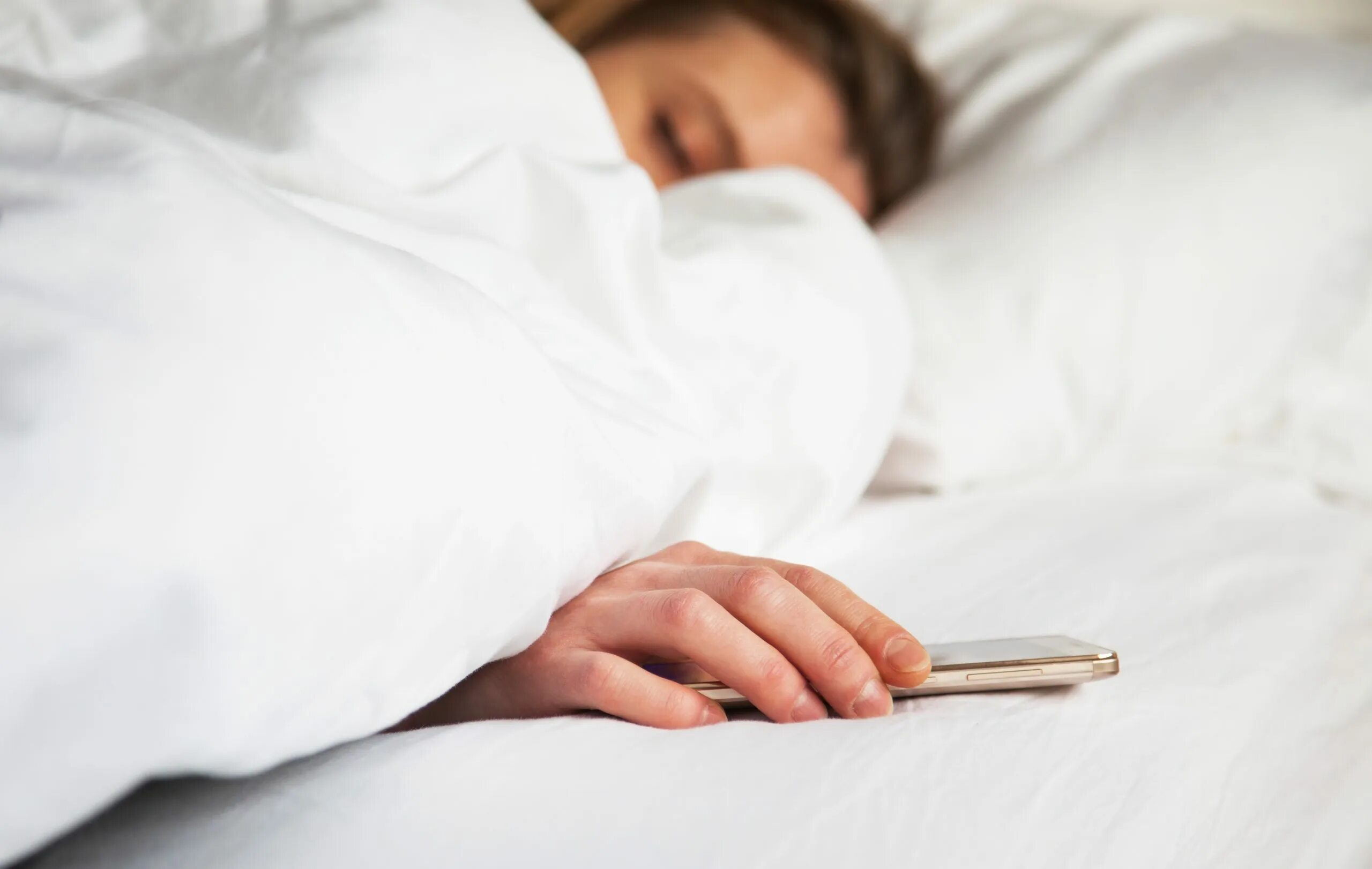 В постели с телефоном. Телефон на кровати. Человек с телефоном в кровати. Фото мужской и женской руки на тумбочке рядом с кроватью.
