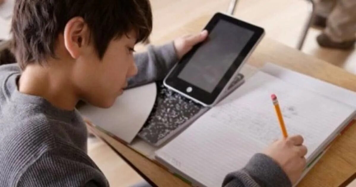 Играет в телефон на уроке. Школьник с планшетом. Смартфон на уроке. Ученик с телефоном. Планшет для детей.