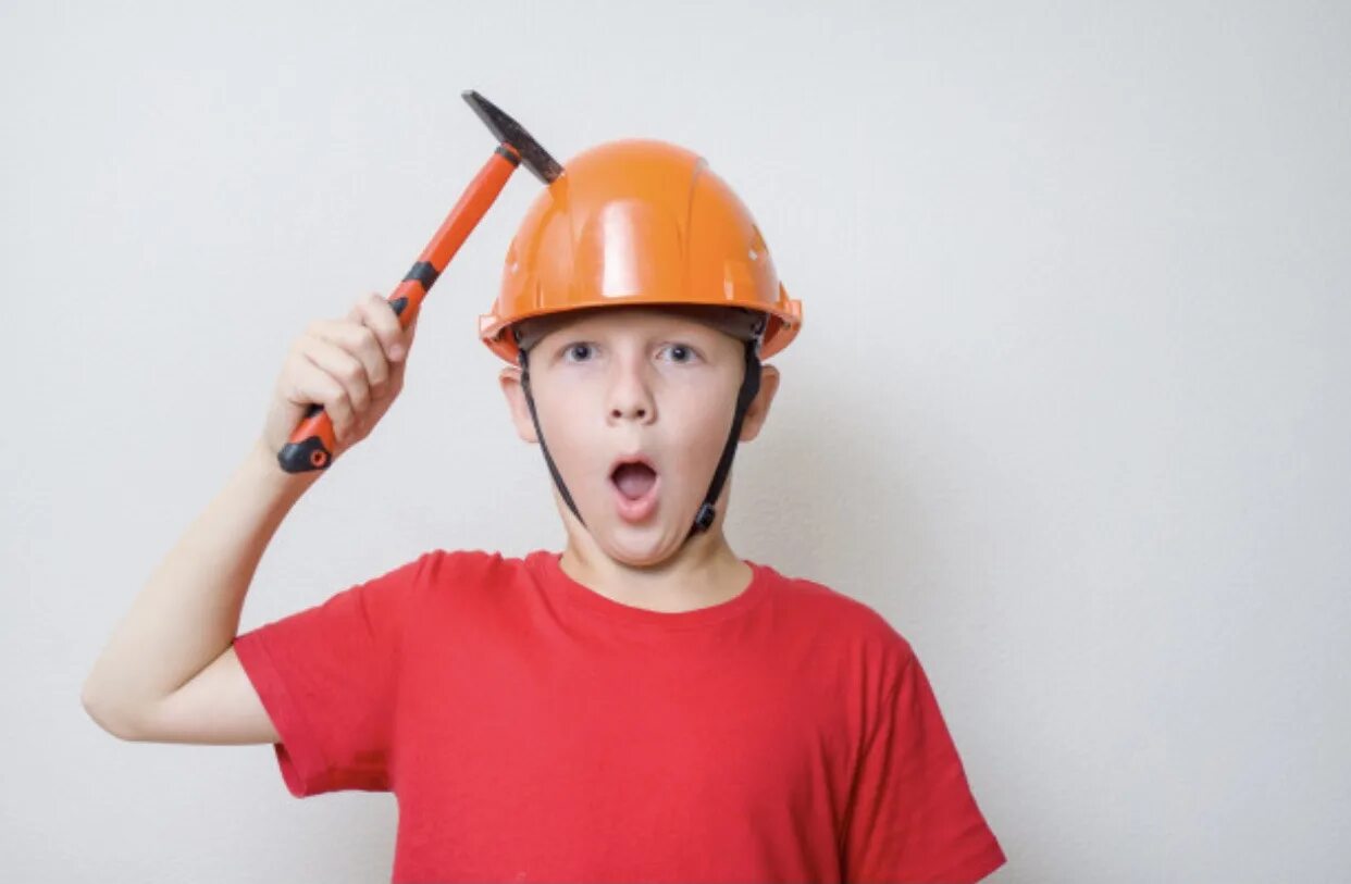 Бьют по каске. Мальчик в каске. по каске молотком. по шлему молотком. ребенок в строительной каске.