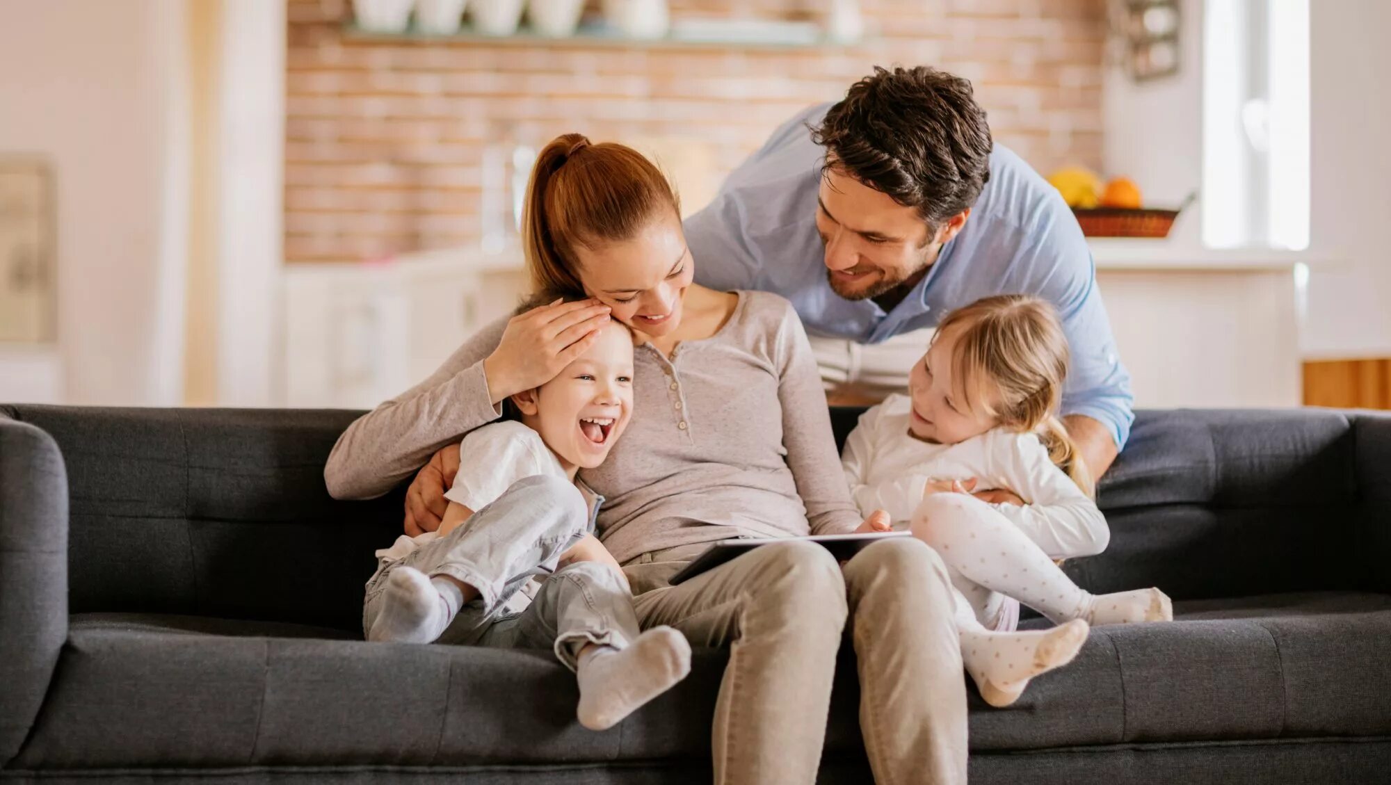 Атмосфера в доме семьи. Ребенок в семье. Родители и дети. Фотография семьи. Счастливая семья на диване.