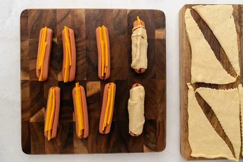 Crescent dough separated into triangles, hot dogs completely wrapped in dou...