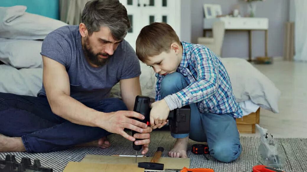 Папа учит ребенка. Папа чинит игрушку. Ребенок помогает папе. Отец обучает сына.