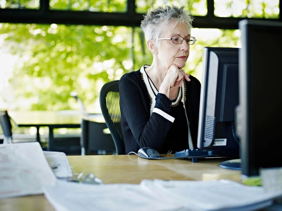 Пожилая женщина в офисе. Женщина в возрасте за компьютером. Пожилая женщина за компьютером. Возрастные работники.