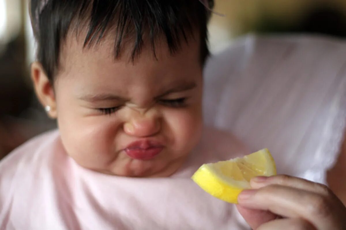 Кислый лимон. Лицо от лимона. Младенец ест лимон. Человек ест лимон.