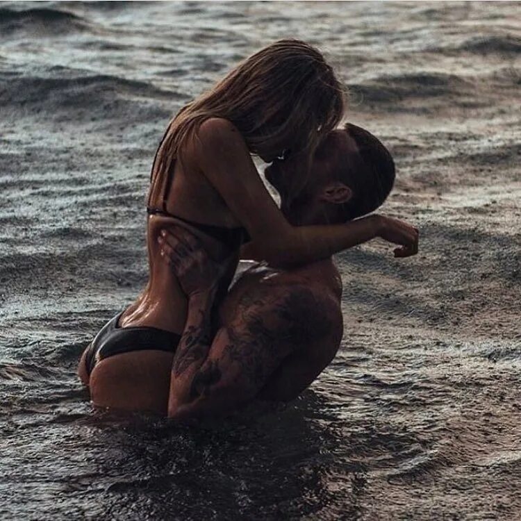 Обнимаются в воде. Страсть на пляже. Мужчина и женщина обнимаются на море. Поцелуй на море. Утопающая страсть