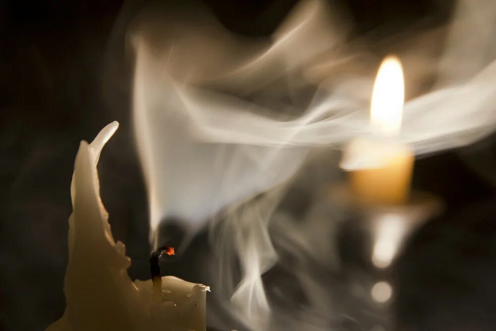 На столе стоит свеча которая отражается. Горящая свеча. Огонь свечи. Погасшая свеча. Потухшая свеча.