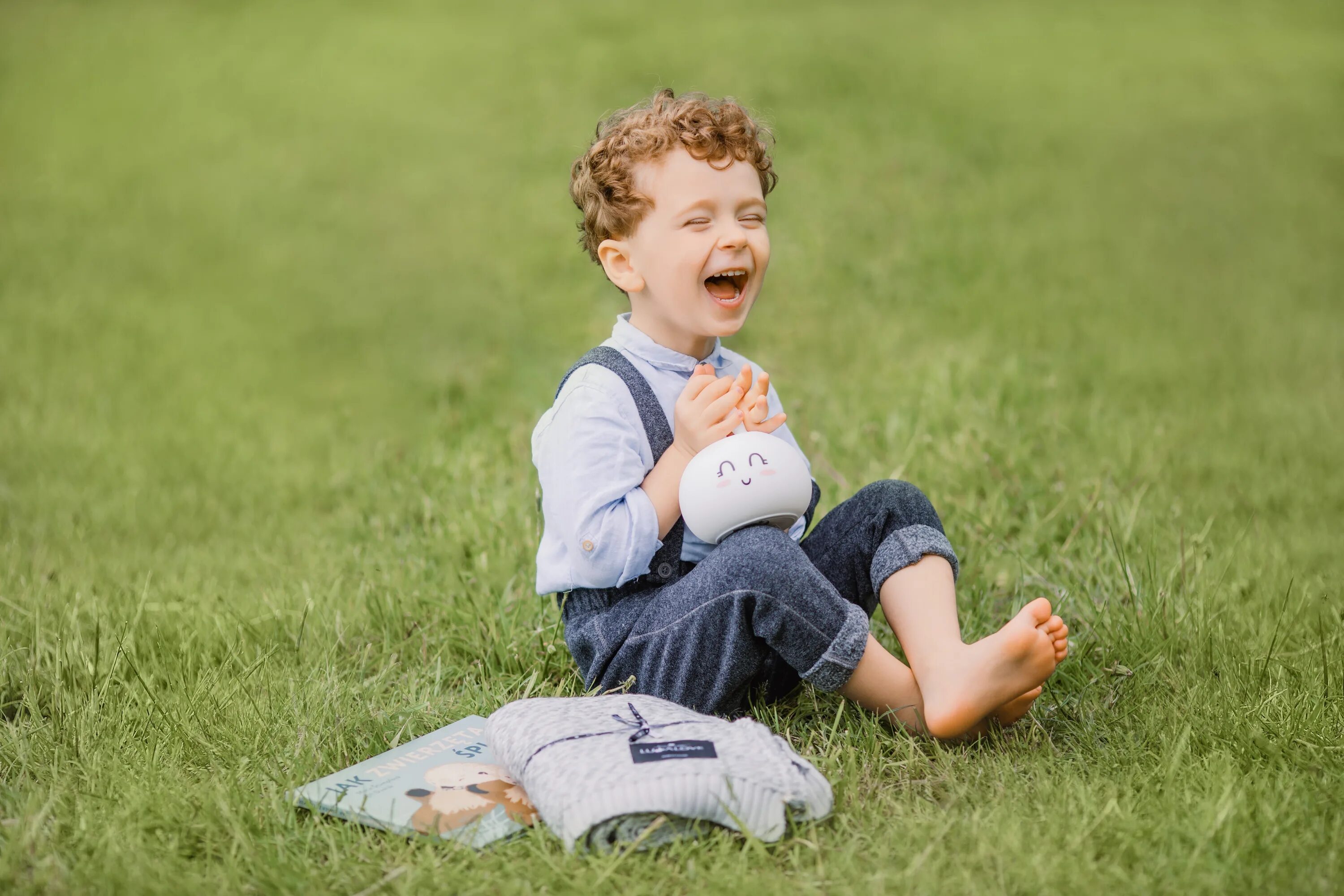 Child focus. Мальчик улыбается. Ребенок. Мальчик сидит на траве. Мальчик смеется.