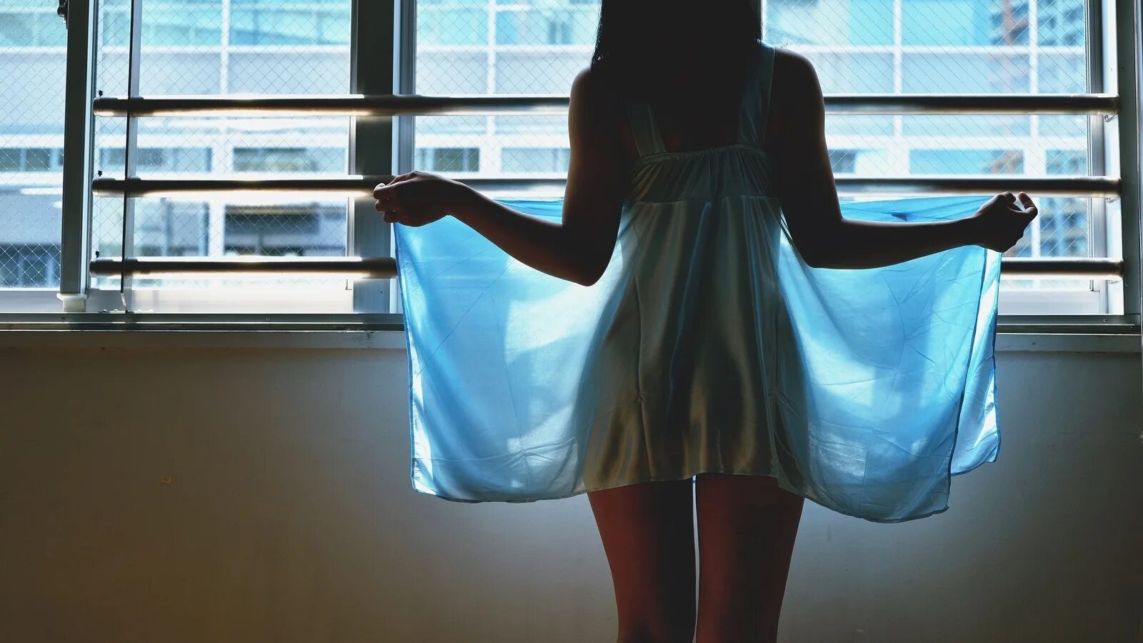 За окном девушка в бежевом платьице слушать. Девушка возле окна спиной. Девушка у окна со спины. Девушка у окна в полотенце. Девушка распахивает окно.