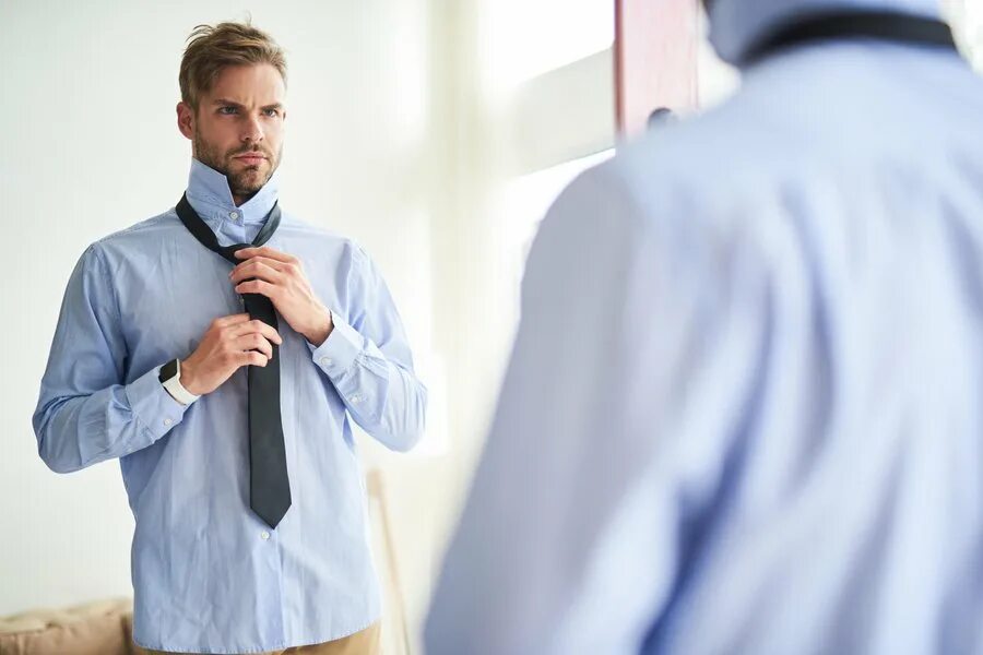 Парень надевает. Мужчина надевает рубашку. Что надеть мужчине. Мужчина одевается. Мужчина надевает галстук перед зеркалом.