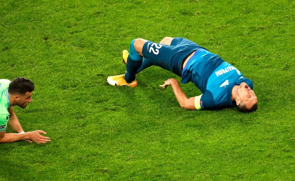Травма паха. Футболист лежит на газоне. Дзюба лежит на поле. Капитанская повязка на футболистах. Капитанская повязка Зенит.