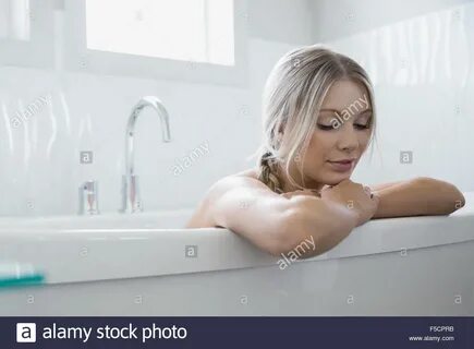 Happy african american woman relaxing in bath, having fun blowing bath foam...